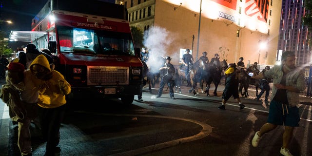 Police on horseback move people back as rowdy fans celebrate, Sunday, Oct. 11, 2020, in Los Angeles, after the Los Angeles Lakers defeated the Miami Heat in Game 6 of basketball's NBA Finals to win the championship. (AP Photo/Jintak Han)