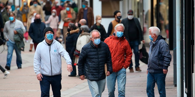 People wearing masks walk down a street in Saint Jean de Luz, southwestern France, Monday, Oct. 12, 2020. Some parts of France have been put on maximum coronavirus alert level, which means shutting down bars, implementing stricter measures in restaurants and limiting private gatherings. (AP Photo/Bob Edme)