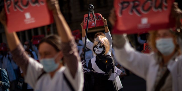 Primary care workers take part in a protest against their working conditions during a strike in Barcelona, Spain, Tuesday, Oct. 13, 2020. Various regions in Spain, including northern Navarra and northeastern Catalonia, are either planning or implementing fresh restrictions against the spread of the new coronavirus. Signs read: "Enough". (AP Photo/Emilio Morenatti)