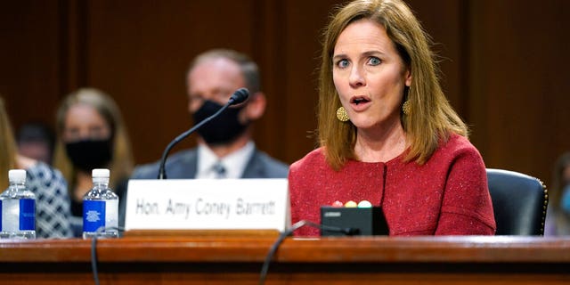 Supreme Court nominee Amy Coney Barrett speaks during a confirmation hearing before the Senate Judiciary Committee, Tuesday, Oct. 13, 2020, on Capitol Hill in Washington. Her family looks on at left. (AP Photo/Patrick Semansky, Pool)