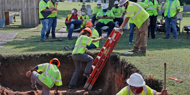 FILE - In this July 14, 2020, file photo, workers climb out of the excavation site as work continues on a potential unmarked mass grave from the 1921 Tulsa Race Massacre, at Oaklawn Cemetery in Tulsa, Okla. (AP Photo/Sue Ogrocki File)