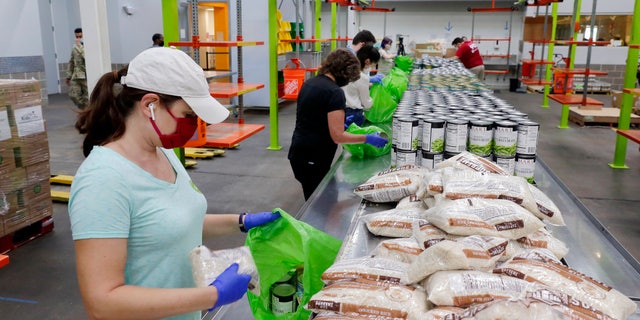 Volunteers load non-perishable foods into green grocery bags for distribution to a local school's food program. (AP Photo/Michael Wyke)