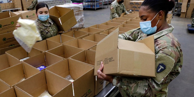 Texas National Guard soldiers Spc. Esmeralda Zuniga, sinistra, and Spc. Samantha McClasky, destra, load boxes with various dairy products at the Houston Food Bank on Oct. 14. (AP Photo/Michael Wyke)