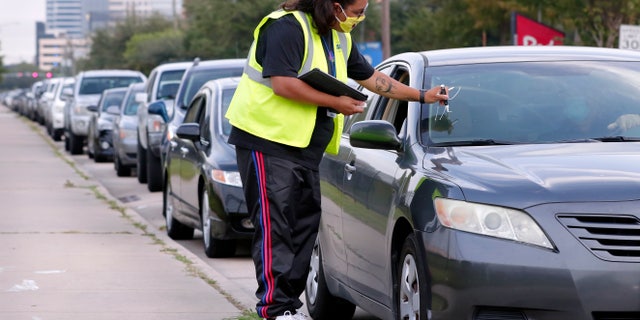 Volunteer Sharely Gomez marks the windshield after taking information from clients in their cars as they wait in line at West Houston Assistance Ministries. (AP Photo/Michael Wyke)