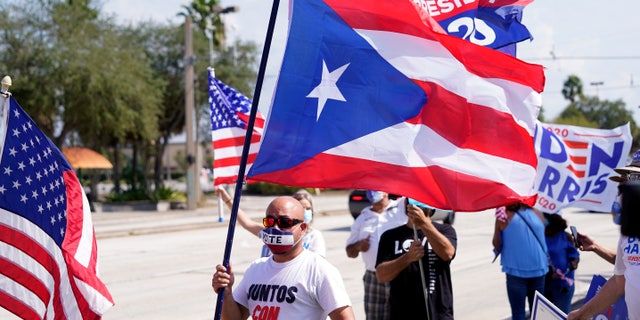 Puerto Rican voter Mel Lopez, president of the Hispanic Caucus of Orange County, waves a Puerto Rican flag during a rally supporting Democratic presidential candidate and former Vice President Joe Biden, Saturday, Oct. 17, 2020, in Orlando, Fla. (AP Photo/John Raoux)
