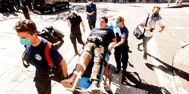 Medics transport a supporter of President Donald Trump to an ambulance after he was attacked by counter-protesters in San Francisco on Saturday, Oct. 17, 2020. About a dozen pro-Trump demonstrators were met by several hundred counter-protesters as they tried to rally. (AP Photo/Noah Berger)