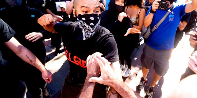 A counter-protester, who declined to give his name, prepares to hit a conservative free speech rally organizer in San Francisco on Saturday, Oct. 17, 2020. About a dozen pro-Trump demonstrators were met by several hundred counter-protesters as they tried to rally. (AP Photo/Noah Berger)