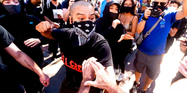 A counter-protester, who declined to give his name, prepares to hit a conservative free speech rally organizer in San Francisco on Saturday, Oct. 17, 2020. About a dozen pro-Trump demonstrators were met by several hundred counter-protesters as they tried to rally. (AP Photo/Noah Berger)