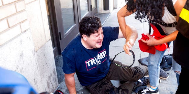 A supporter of President Donald Trump lies on the ground after he was attacked by counterprotesters in San Francisco, Saturday, Oct. 17, 2020. About a dozen pro-Trump demonstrators were met by several hundred counterprotesters as they tried to rally. (AP Photo/Noah Berger)