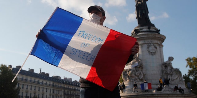 A demonstrator holds a French flag with the slogan "Freedom of Speech" during a demonstration Sunday Oct. 18, 2020 in Paris. Demonstrations around France have been called in support of freedom of speech and to pay tribute to a French history teacher who was beheaded near Paris after discussing caricatures of Islam's Prophet Muhammad with his class. Samuel Paty was beheaded on Friday by a 18-year-old Moscow-born Chechen refugee who was shot dead by police. (AP Photo/Michel Euler)