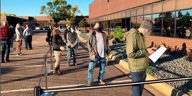 In this Sept. 8, 2020 file photo voters line up outside of the Minneapolis early voting center as Minnesota opened early voting for the general election. (AP Photo/Steve Karnowski, File)