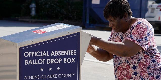 A voter drops their ballot off during early voting, Monday, Oct. 19, 2020, in Athens, Ga. (AP Photo/John Bazemore)