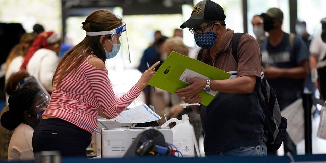 An election worker, left, gives instructions for voting at an early voting site, Monday, Oct. 19, 2020, in Miami. (AP Photo/Lynne Sladky)