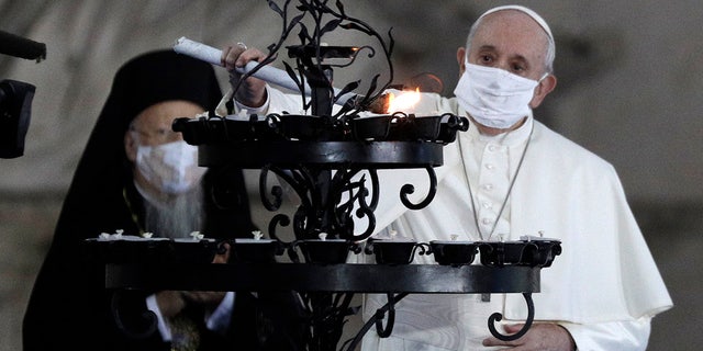 Pope Francis lights a candle for peace during an inter-religious ceremony for peace in the square outside Rome's City Hall, Tuesday, Oct. 20, 2020 (AP Photo/Gregorio Borgia)
