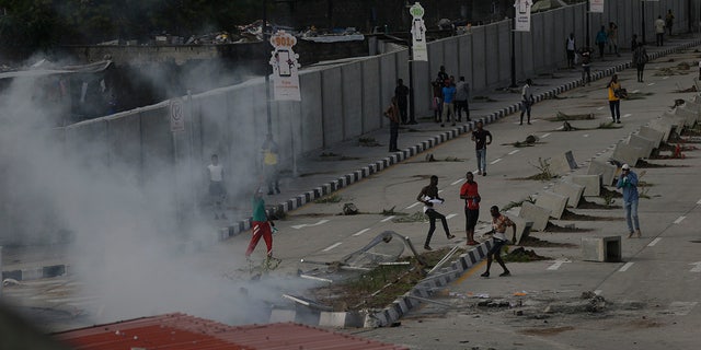 Protesters run away as police officers use tear gas to disperse people demonstrating against police brutality in Lagos, Nigeria, Wednesday Oct. 21, 2020. ( AP Photo/Sunday Alamba)