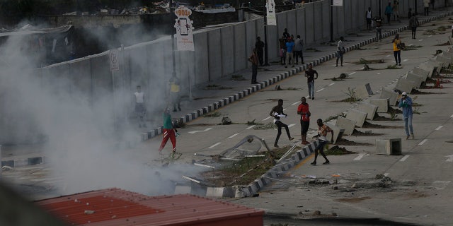 Protesters run away as police officers use teargas to disperse people demonstrating against police brutality in Lagos, Nigeria, Wednesday Oct. 21, 2020. After 13 days of protests against alleged police brutality, authorities have imposed a 24-hour curfew in Lagos, Nigeria's largest city, as moves are made to stop growing violence. ( AP Photo/Sunday Alamba)