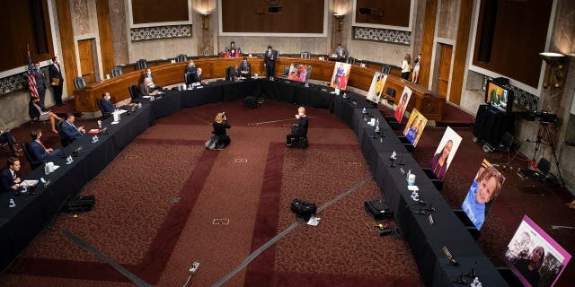 Images of people who've been helped by the Affordable Care Act (ACA) occupy the seats of Democratic senators boycotting a Senate Judiciary Committee business meeting on the nomination of Judge Amy Coney Barrett to be an associate justice of the U.S. Supreme Court, Thursday, Oct. 22, 2020 on Capitol Hill in Washington. (Caroline Brehman/Pool via AP)