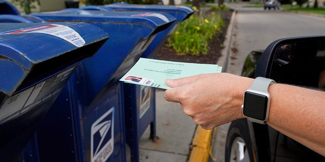 A person drops applications for mail-in-ballots into a mailbox in Omaha, Neb.  (AP Photo/Nati Harnik, File)