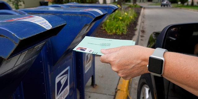 A person drops applications for mail-in-ballots into a mailbox in Omaha, Neb on Aug. 18, 2020. (AP Photo/Nati Harnik, File)