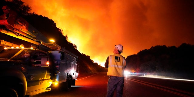 In this Tuesday, Sept. 8, 2020 file photo, A Pacific Gas and Electric worker looks up at the advancing Creek Fire along Highway 168 near Alder Springs, Calif. Pacific Gas &amp; Electric will cut power to over 1 million people on Sunday to prevent the chance of sparking wildfires as extreme fire weather returns to the region, the utility announced Friday. Oct. 23, 2020. (AP Photo/Marcio Jose Sanchez, File)
