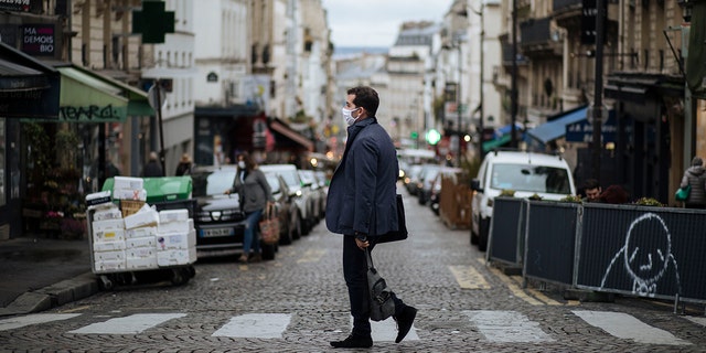 A man wearing a mask walks in the Montmartre district of Paris, Sunday, Oct.25, 2020. (AP Photo/Lewis Joly)