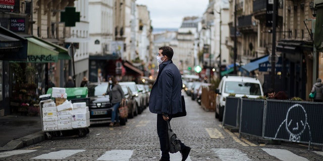 A man wearing a mask walks in the Montmartre district of Paris, Sunday, Oct.25, 2020. (AP Photo/Lewis Joly)