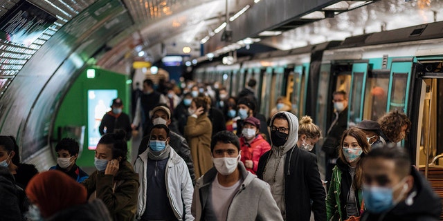Commuters wearing face masks walk on the platform, of a Paris subway, Sunday Oct.25, 2020. (AP Photo/Lewis Joly)