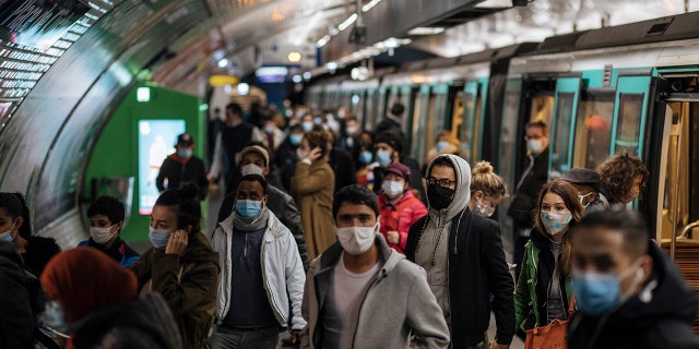 Commuters wearing face masks walk on the platform, of a Paris subway, Sunday Oct.25, 2020. (AP Photo/Lewis Joly)