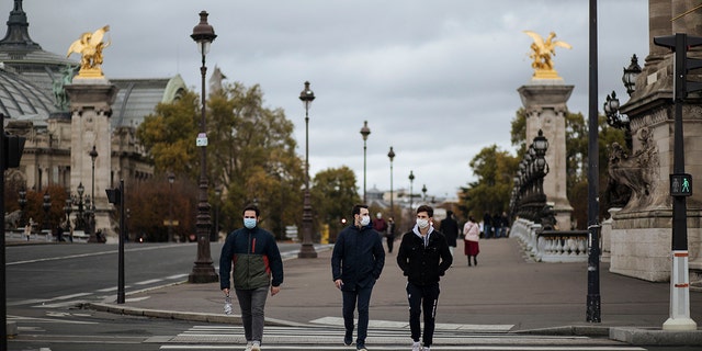 People wearing masks, walk in the Invalides district of Paris, Sunday, Oct.25, 2020. (AP Photo/Lewis Joly)