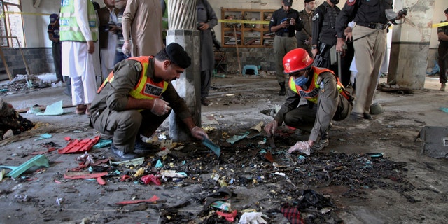 Rescue workers and police officers examine the site of a bomb explosion in an Islamic seminary in Peshawar, Pakistan, Tuesday, Oct. 27, 2020. (AP Photo/Muhammad Sajjad)