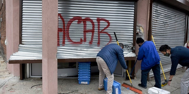 People clean up debris Tuesday after a protest in Philadelphia over the death of Walter Wallace, a Black man who was killed by police in Philadelphia. (AP Photo/Michael Perez)