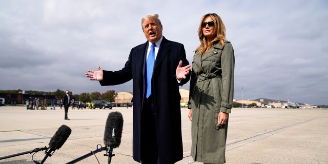 President Trump talks to reporters as first lady Melania Trump listens before boarding Air Force One for a day of campaign rallies in Michigan, Wisconsin, and Nebraska, Tuesday, Oct. 27, 2020, at Andrews Air Force Base, Md. (AP Photo/Evan Vucci)