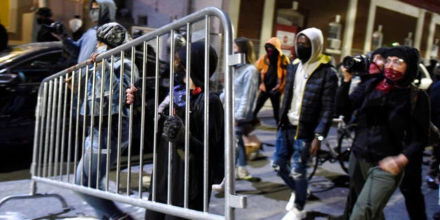 Protesters, including two carrying part of a barricade, walk during a demonstration Tuesday night, Oct. 27, 2020, in Philadelphia. (AP Photo/Michael Perez)