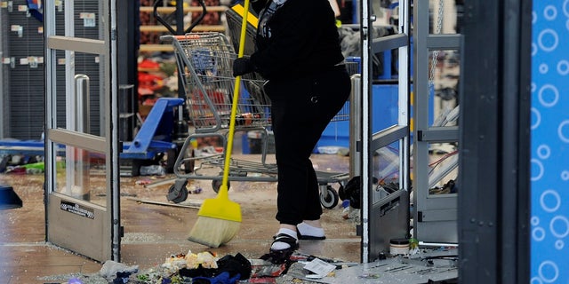 A woman cleans up debris at a Walmart that was damaged in Wednesday night protests in Philadelphia. (AP Photo/Michael Perez)