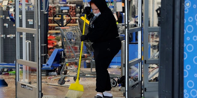 A woman cleans up debris at a Walmart that was damaged in Wednesday night protests in Philadelphia. (AP Photo/Michael Perez)