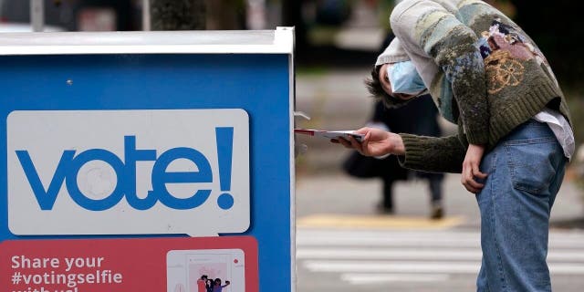 A voter watches the opening of a ballot box before casting their ballot inside Wednesday, Oct. 28, 2020 in Seattle. (AP Photo/Elaine Thompson)