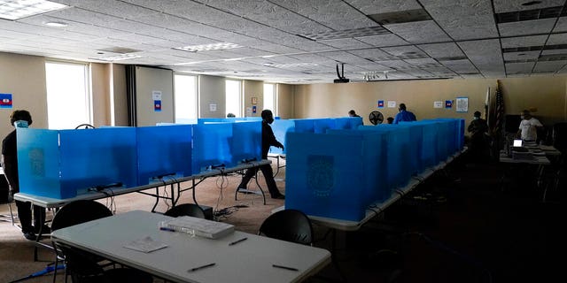 Poll workers walk through dark voting booths during early voting at the Dunwoody Library after Hurricane Zeta knocked out power in the surrounding areas on Oct. 29, in Dunwoody, Ga.<br> (美联社照片/布林·安德森)