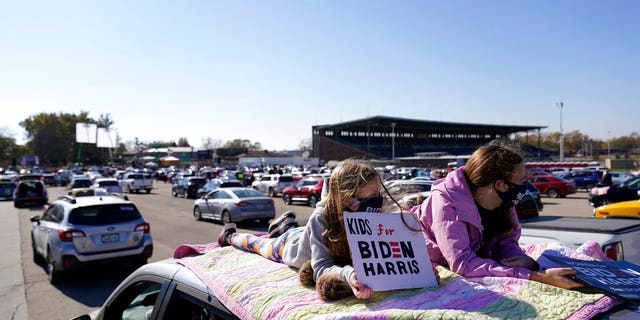 Children lie on the roof of a vehicle during a campaign rally for Democratic presidential candidate former Vice President Joe Biden at the Iowa State Fairgrounds in Des Moines, Iowa, Friday, Oct. 30, 2020. (AP Photo/Andrew Harnik)