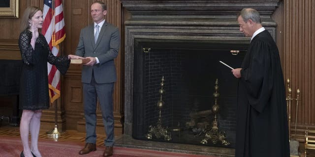 Chief Justice John G. Roberts, Jr., administers the Judicial Oath to Judge Amy Coney Barrett in the East Conference Room, Supreme Court Building. Judge Barrett’s husband, Jesse M. Barrett, holds the Bible. (Credit: Fred Schilling, Collection of the Supreme Court of the United States)