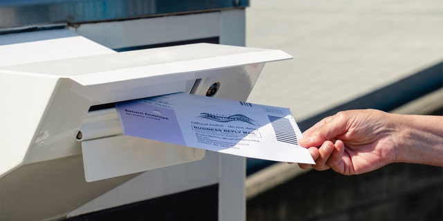 A voter drops off a mail-in ballot in Everett, Washington, July 30, 2020.