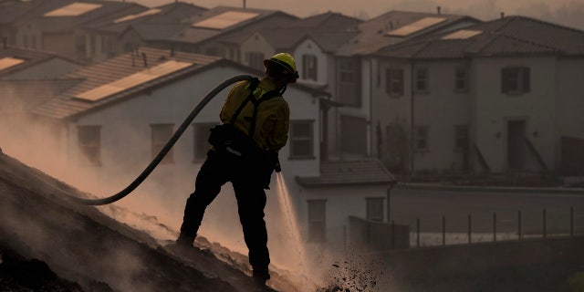 Firefighter Tylor Gilbert puts out hotspots while battling the Silverado Fire, Monday, Oct. 26, 2020, in Irvine, Calif.