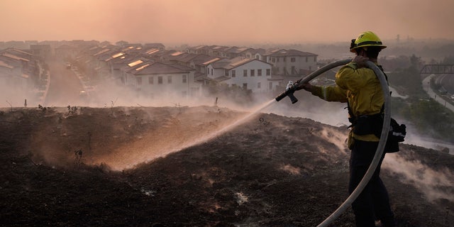 Firefighter Tylor Gilbert puts out hotspots while battling the Silverado Fire, Monday, Oct. 26, 2020, in Irvine, Calif.