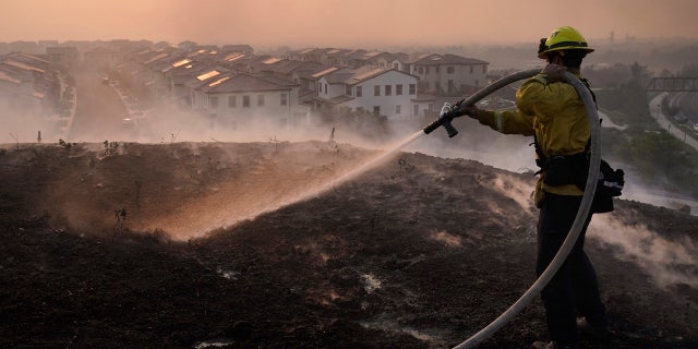 Firefighter Tylor Gilbert puts out hotspots while battling the Silverado Fire, Monday, Oct. 26, 2020, in Irvine, Calif.