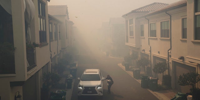 A man leaves his home during a mandatory fire evacuation as smoke from the Silverado Fire fills the air, Monday, Oct. 26, 2020, in Irvine, Calif.