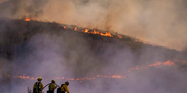 Firefighters watch as the Blue Ridge Fire burns along the 71 state highway Tuesday, Oct. 27, 2020, in Chino Hills, Calif.