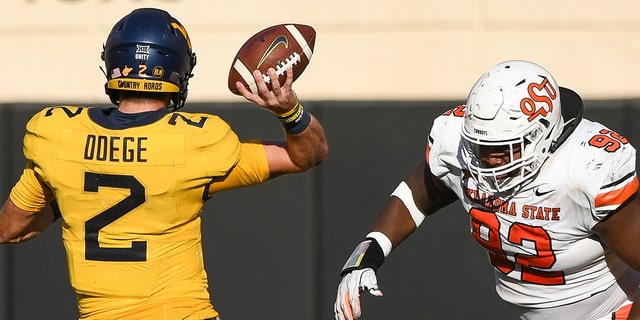 Oklahoma State defensive tackle Cameron Murray (92) runs toward West Virginia quarterback Jarret Doege (2) during the first half of an NCAA college football game Saturday, Sept. 26, 2020, in Stillwater, Okla. (AP Photo/Brody Schmidt)