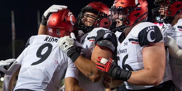 Cincinnati quarterback Desmond Ridder (9) is congratulated by offensive linemen Vincent McConnell, center, and Jake Renfro (56) after a touchdown run against SMU during the second half of an NCAA college football game Saturday, Oct. 24, 2020, in Dallas. (AP Photo/Jeffrey McWhorter)