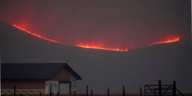 Flames rise from mountain ridges as a wildfire burns near Granby, Colo., on Thursday, Oct. 22, 2020.
