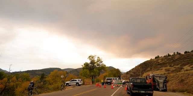 A funnel of smoke builds over a roadblock into a housing area along Highway 7 as several wildfires burn in the state Wednesday, Oct. 21, 2020, in Lyons, Colo.
