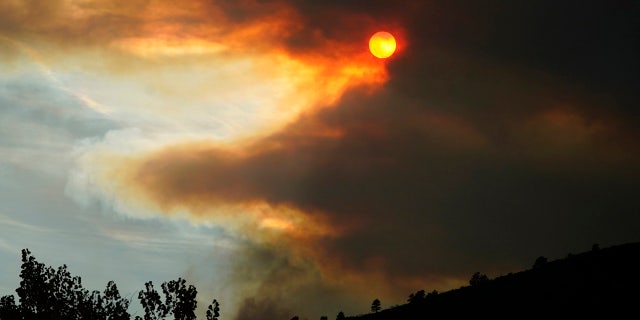 Smoke obscures the sun as fire approaches a ridge along Highway 36 as several wildfires burn in the state Wednesday, Oct. 21, 2020, south of Lyons, Colo.